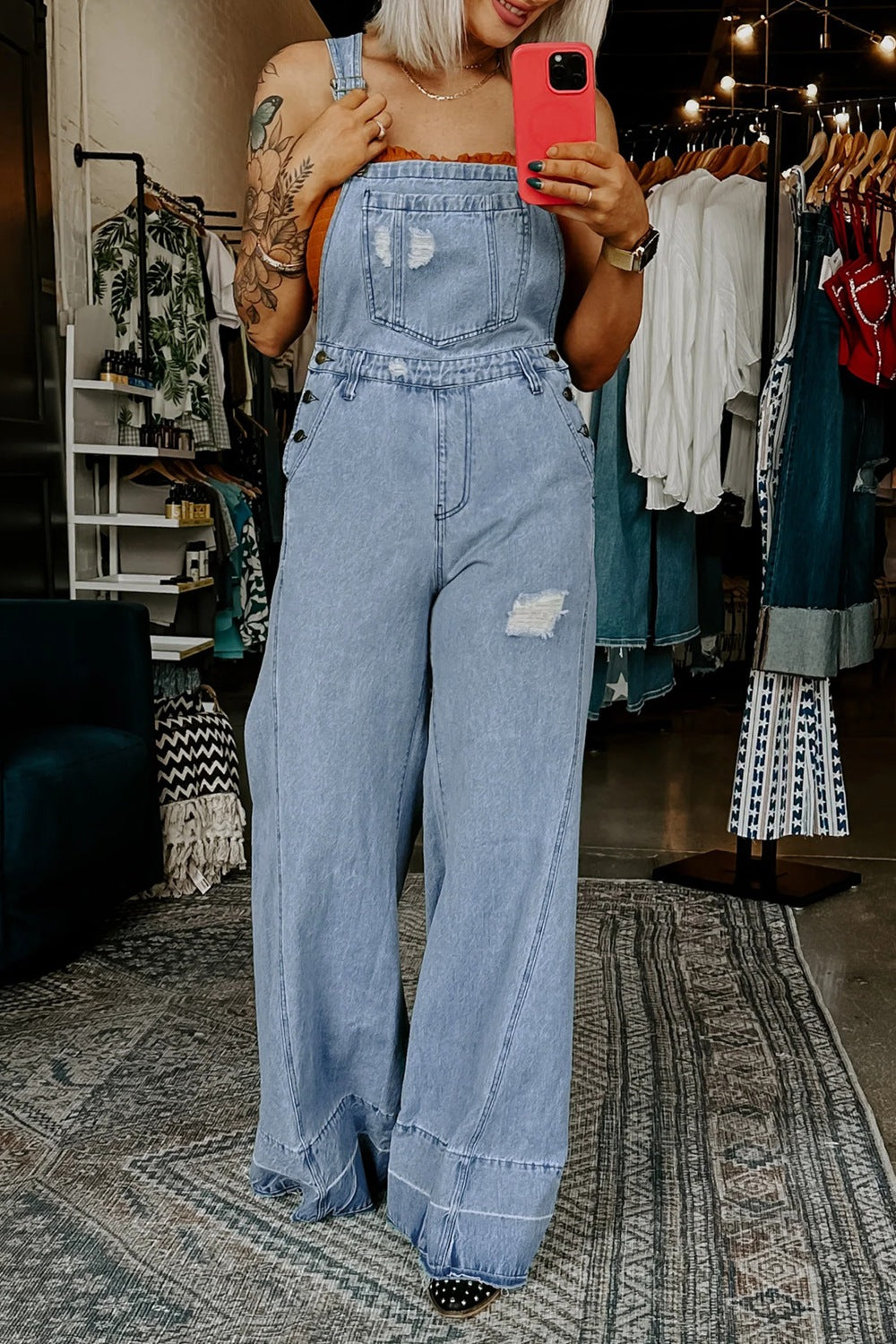 Distressed light wash denim wide-leg overalls with a bib pocket and button details.