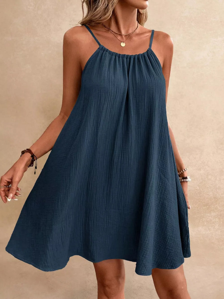 Denim blue cotton gauze spaghetti strap dress with gathered neckline and A-line skirt.