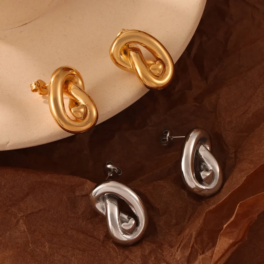 Gold and silver sculptural knot stud earrings with heart detail