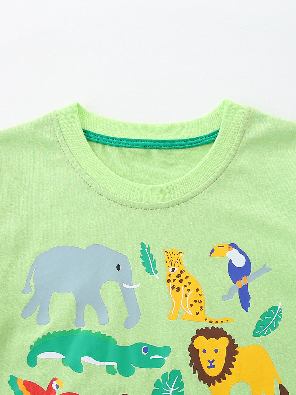 Light green cotton crew neck t-shirt with playful animal print featuring elephant, leopard, toucan, alligator, and lion.