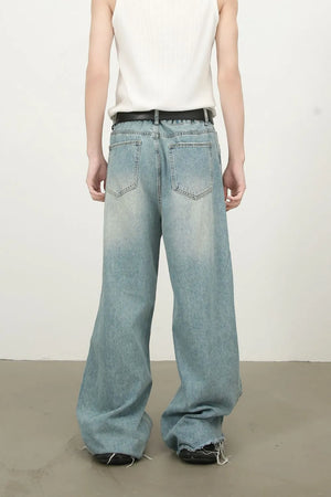 Distressed wide-leg denim jeans in medium wash with fraying hem.
