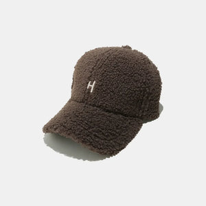 Textured sherpa baseball cap in coffee brown with embroidered white "H" detail.