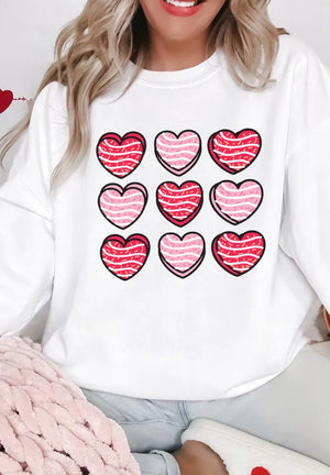 White crewneck sweatshirt with a grid of nine hearts, featuring pink and red stripes inside.