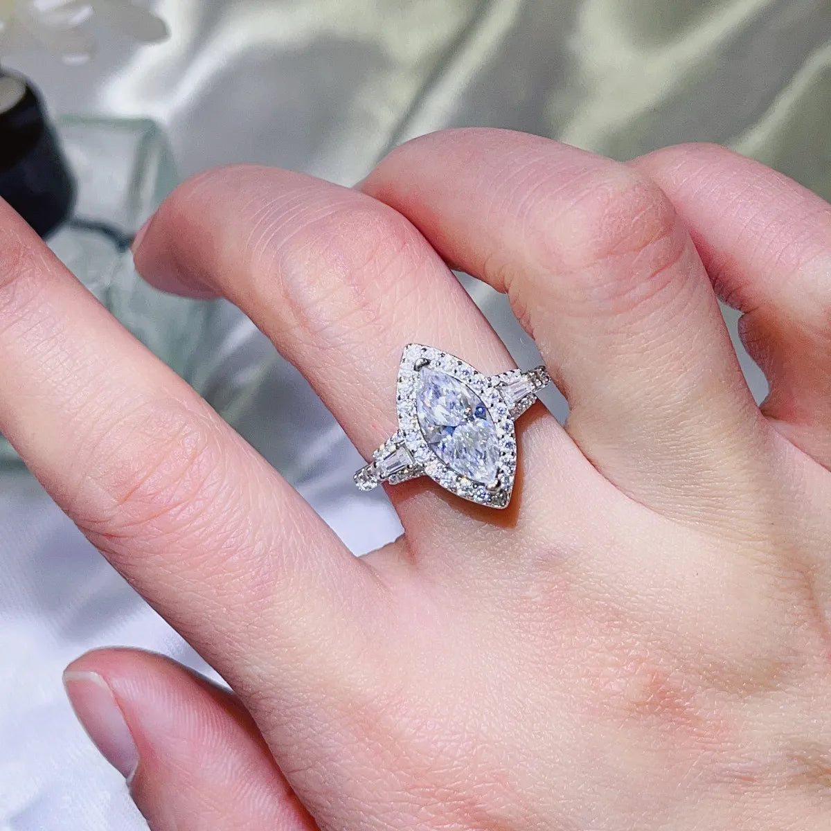White marquise halo moissanite engagement ring with baguette and round accent stones.