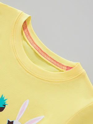 Yellow crew neck t-shirt with pink stitching detail and partial view of animal face graphic.