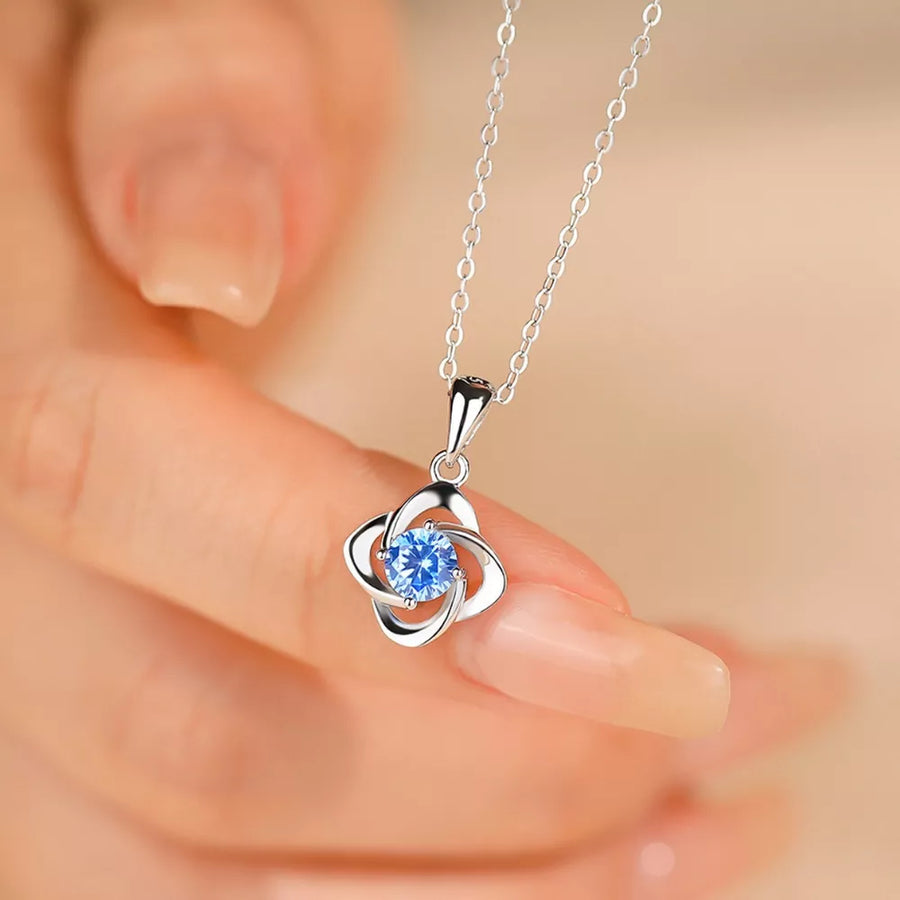 Delicate silver four-leaf clover necklace with blue crystal charm on a fine chain.