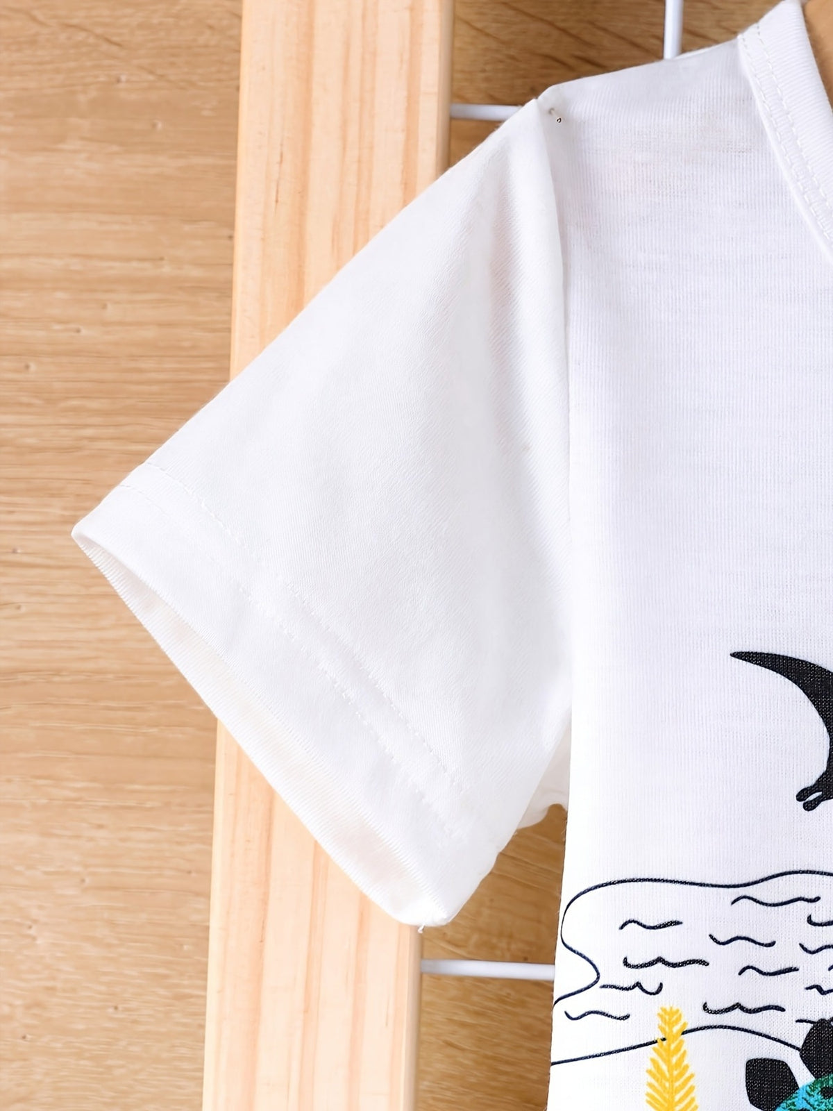 White baby tee with short sleeves and a dinosaur adventure graphic print.