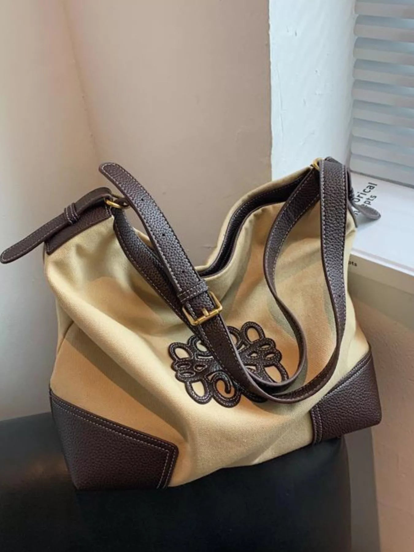 Khaki canvas tote bag with brown leather trim and embroidered detail