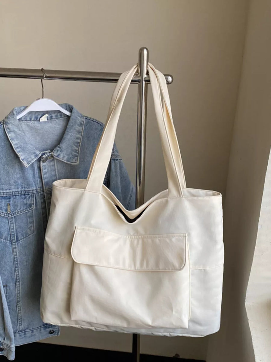 Spacious cream nylon shoulder bag with flap pocket and top handles.