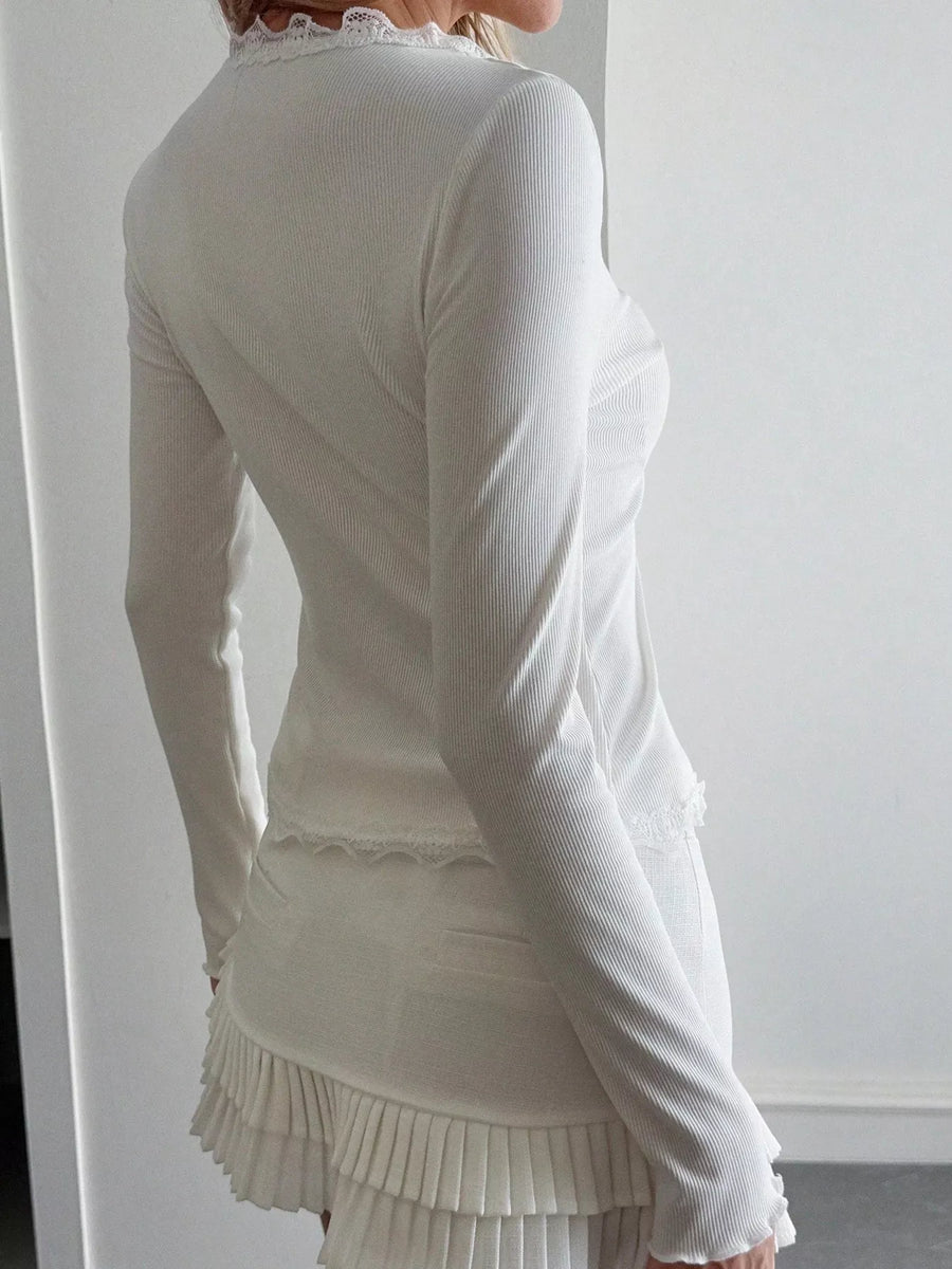 White ribbed long sleeve top with lace trim at neckline and hem.