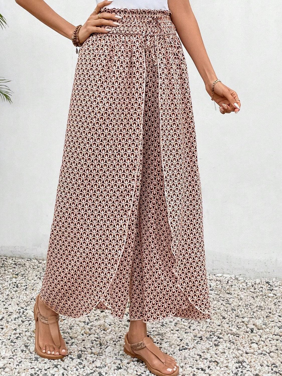 Palazzo pants with a geometric print in blush pink and black, featuring a wrap-front design and smocked waist.