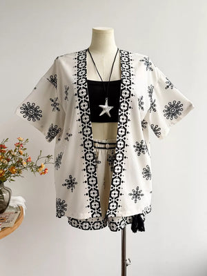 White polyester shorts and open cardigan set with black geometric and snowflake print.