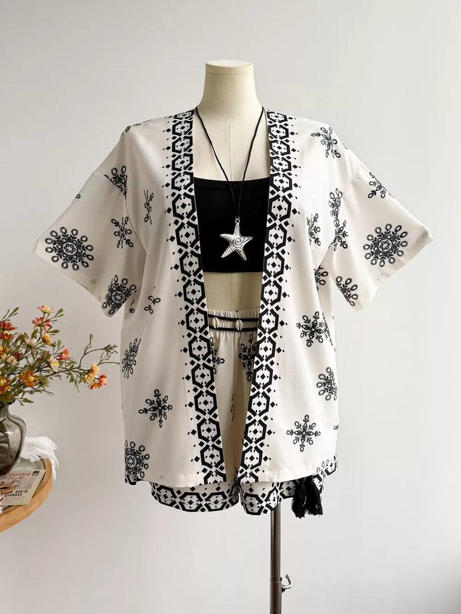 White polyester shorts and open cardigan set with black geometric and snowflake print.