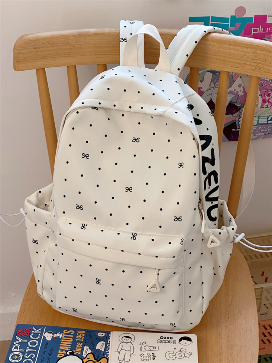 White polka dot backpack with bowknot pattern and side pockets.
