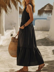 Black sleeveless maxi dress with ruffled hem and pockets, worn with sandals.