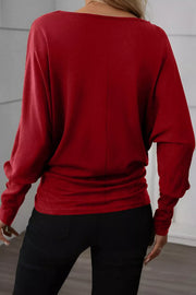 Burgundy long-sleeve blouse with a draped fit and gathered waist detail.