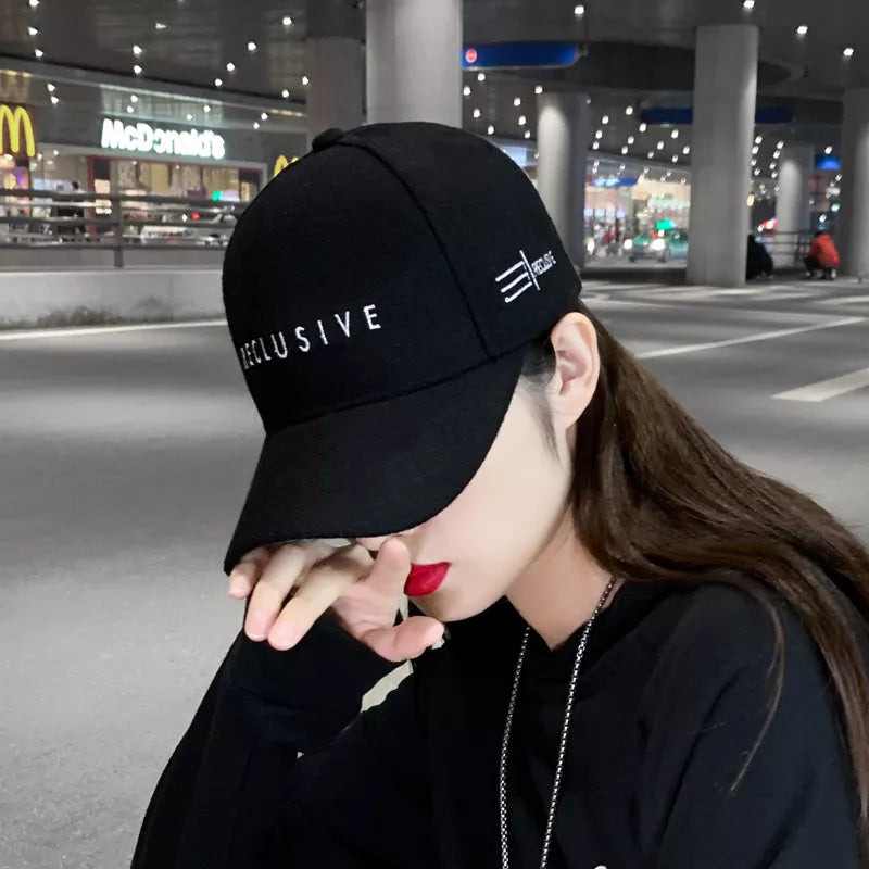 Black cotton baseball cap with white "RECLUSIVE" embroidery and side logo detail.