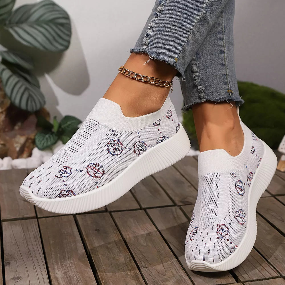 White breathable mesh slip-on sneakers with a patterned design and white soles.