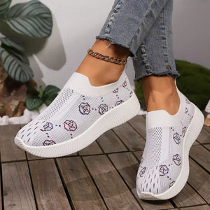 White breathable mesh slip-on sneakers with a patterned design and white soles.