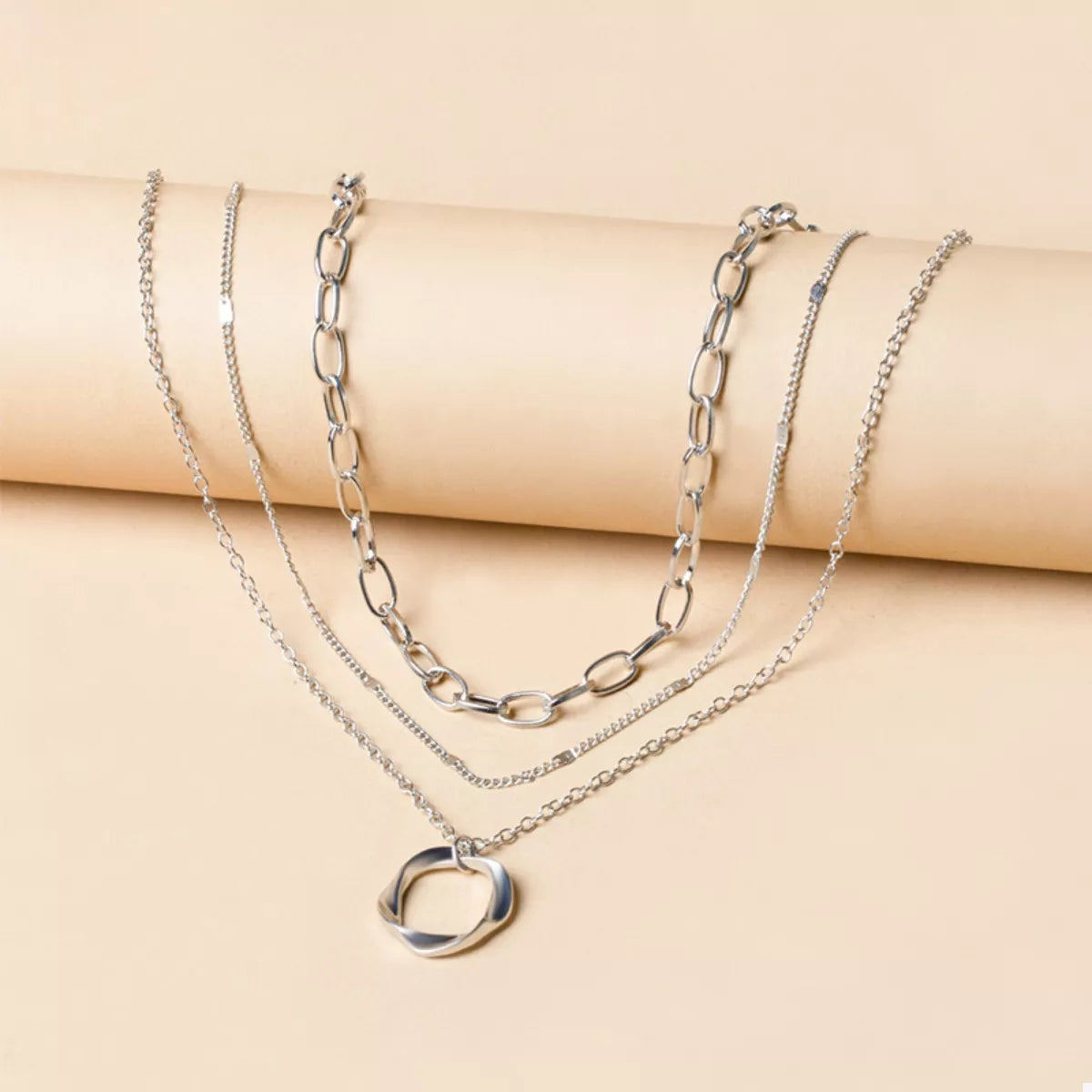 Layered silver necklace with chunky and delicate chains and a twisted circle pendant.