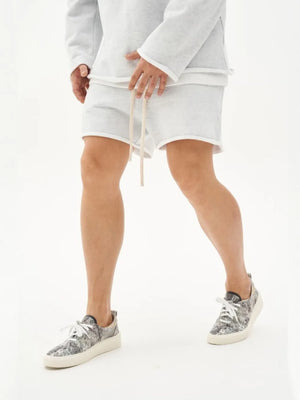 Gray fleece lounge shorts with raw edge hem and drawstring, paired with patterned sneakers.
