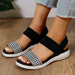 Black and white houndstooth elastic strap sandals with white soles.