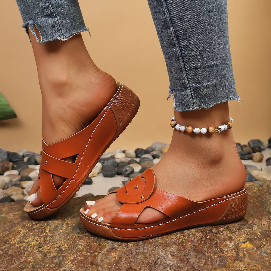 Orange slip-on wedge sandals with crisscross straps and riveted detail.