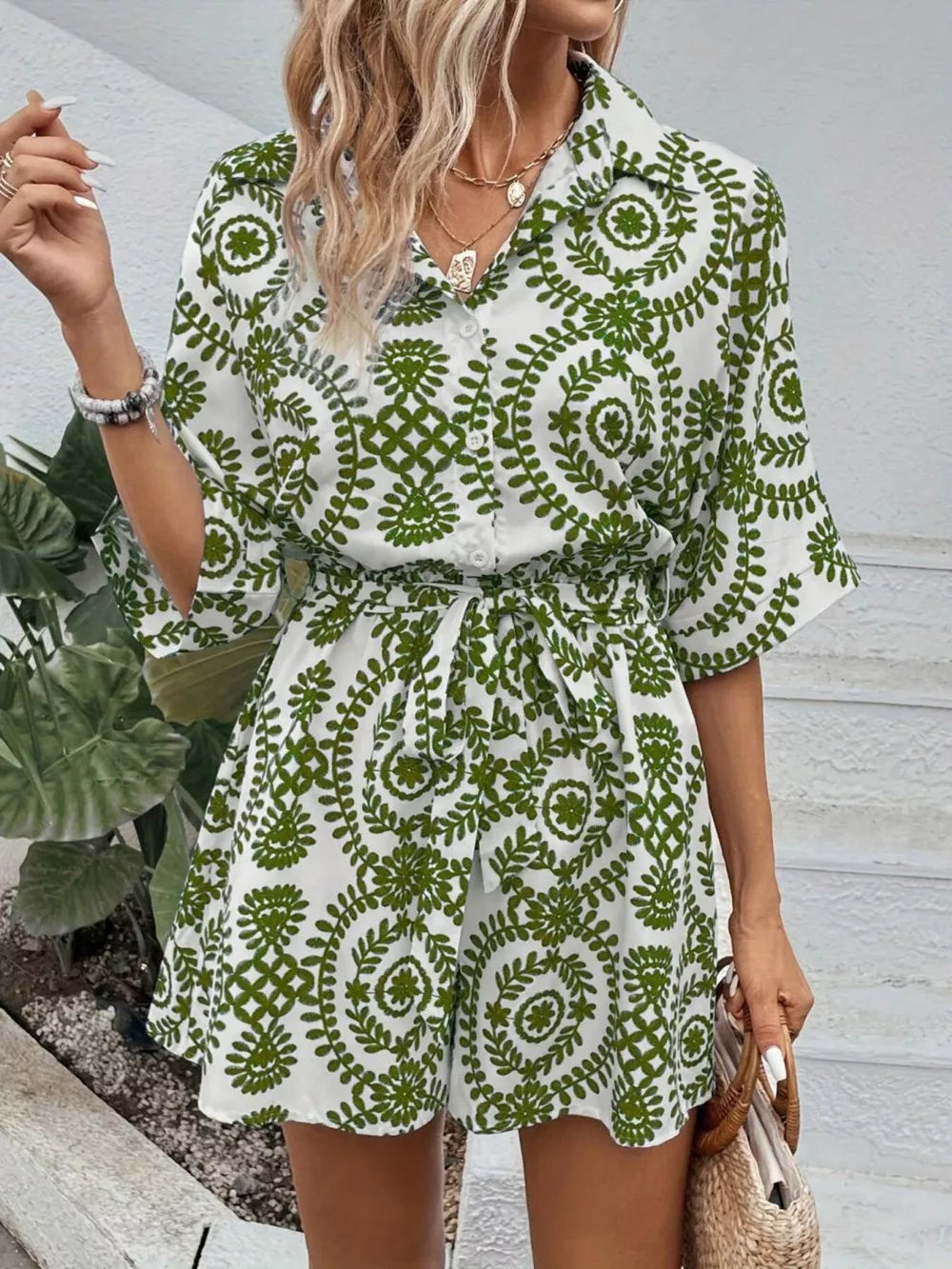 Green printed tie-waist romper with button front and short sleeves.