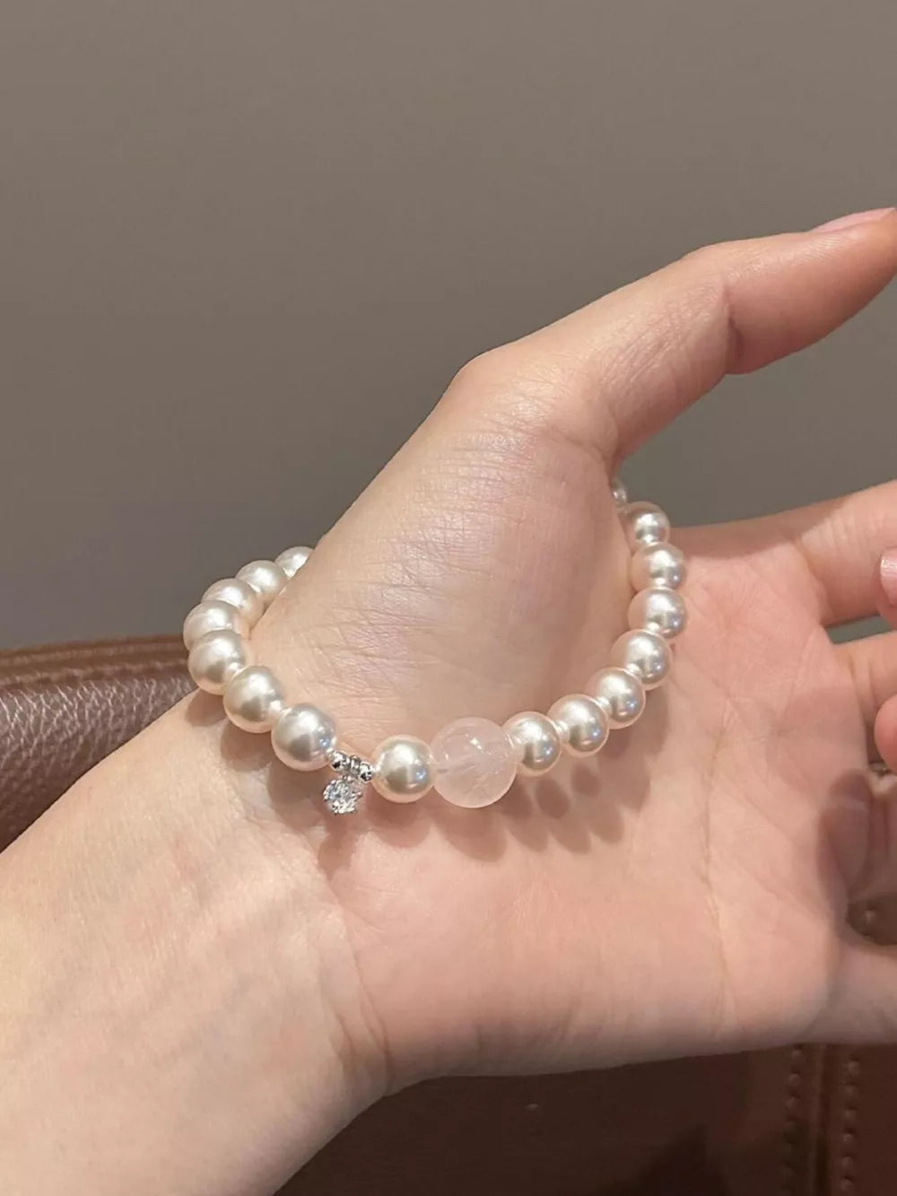 Lustrous pearl charm bracelet with rose quartz and zircon detail on wrist