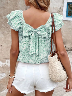 Green floral ruffle blouse with back bow detail and short sleeves.
