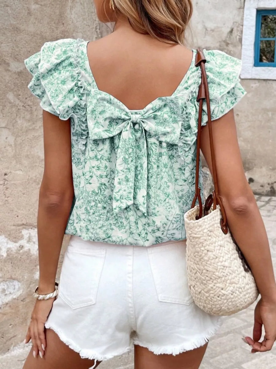 Green floral ruffle blouse with back bow detail and short sleeves.