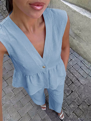 Light blue linen blend peplum top with V-neck and button detail, paired with wide-leg pants.