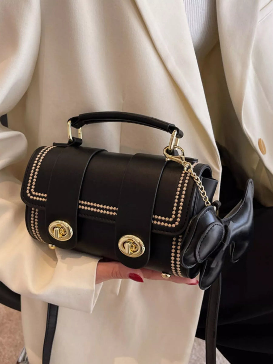 Black PU leather crossbody bag with gold hardware, studded trim, and bow charm.