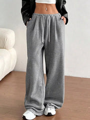 Gray wide-leg lounge pants with drawstring and pockets, styled with a white crop top and black jacket.