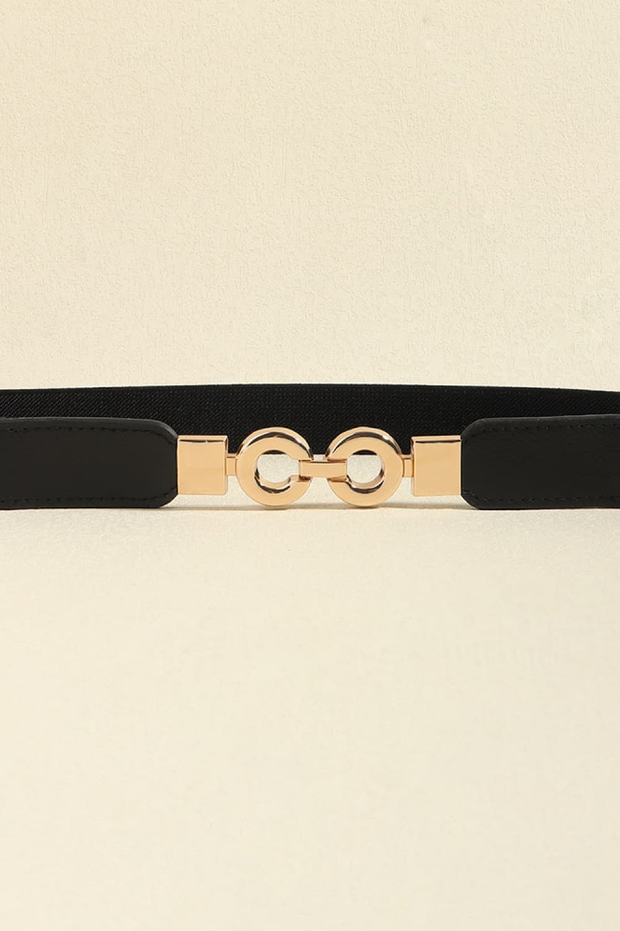 Black elastic belt with gold interlocking circle buckle and faux leather accents.