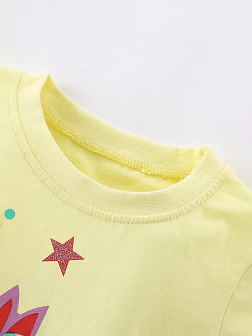 Yellow cotton blend t-shirt with unicorn graphic, stars, and polka dots.