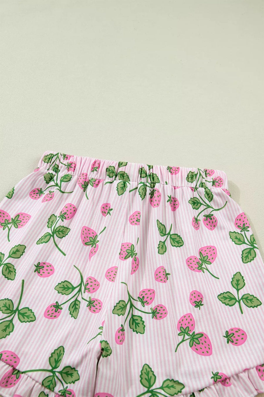 Pink striped pajama shorts with a strawberry print and ruffled hem.