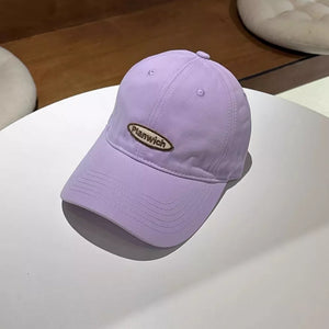Lavender baseball cap with embroidered oval logo detail and curved brim.
