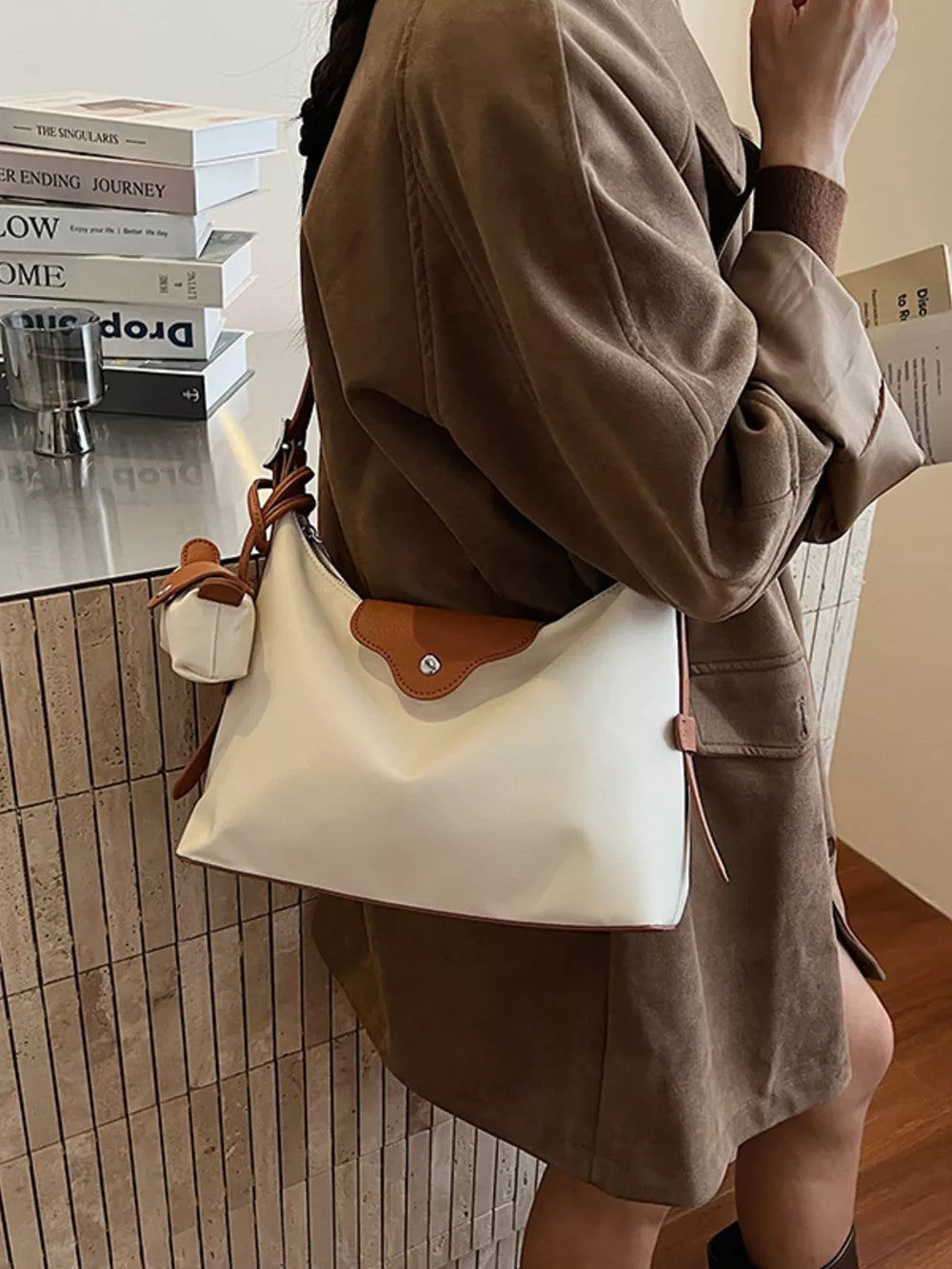 Ivory canvas hobo bag with coin purse and brown trim, worn crossbody.