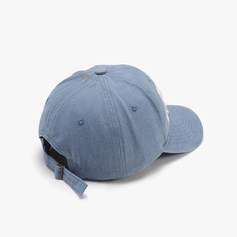 Distressed denim baseball cap in light blue with adjustable strap and patches.