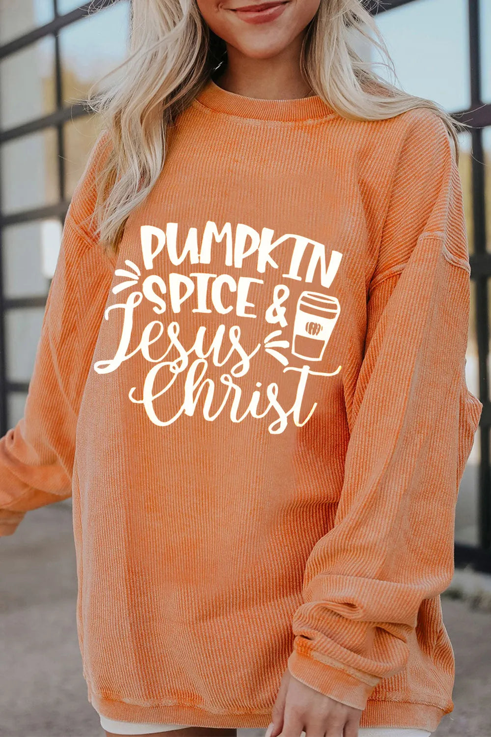 Textured corded orange graphic sweatshirt with "Pumpkin Spice & Jesus Christ" text and coffee cup graphic.