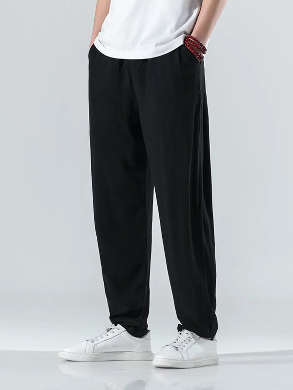 Men's black relaxed fit casual sweatpants with pockets, styled with a white t-shirt and sneakers.