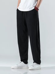 Men's black relaxed fit casual sweatpants with pockets, styled with a white t-shirt and sneakers.