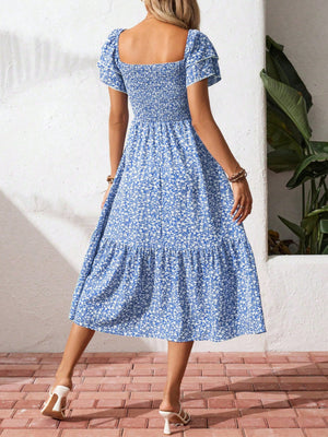 Blue floral smocked midi dress with ruffle sleeves and tiered skirt.