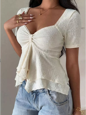 Cream textured peplum top with sweetheart neckline, short sleeves, and ruffled hem.