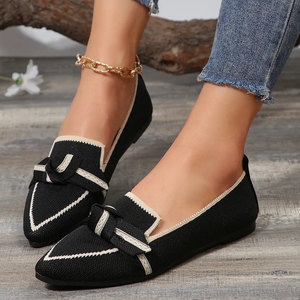Black mesh slip-on flats with cream trim and bow detail.
