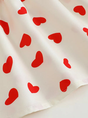 Baby dress with red heart print on white cotton fabric