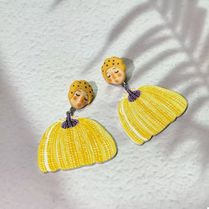 Yellow dangle earrings with whimsical pumpkin girl faces and patterned skirts
