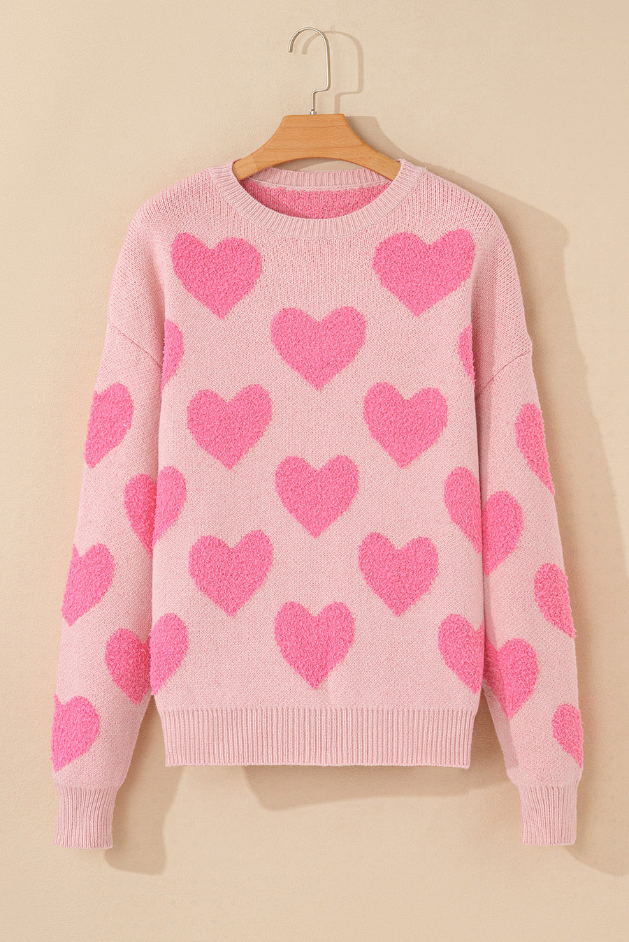 Blush pink knit sweater with allover textured heart motif and crewneck.