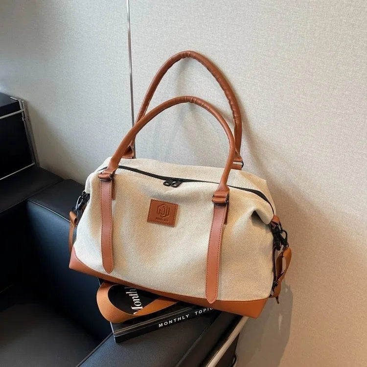 Canvas weekend holdall duffel bag with brown leather trim and handles.